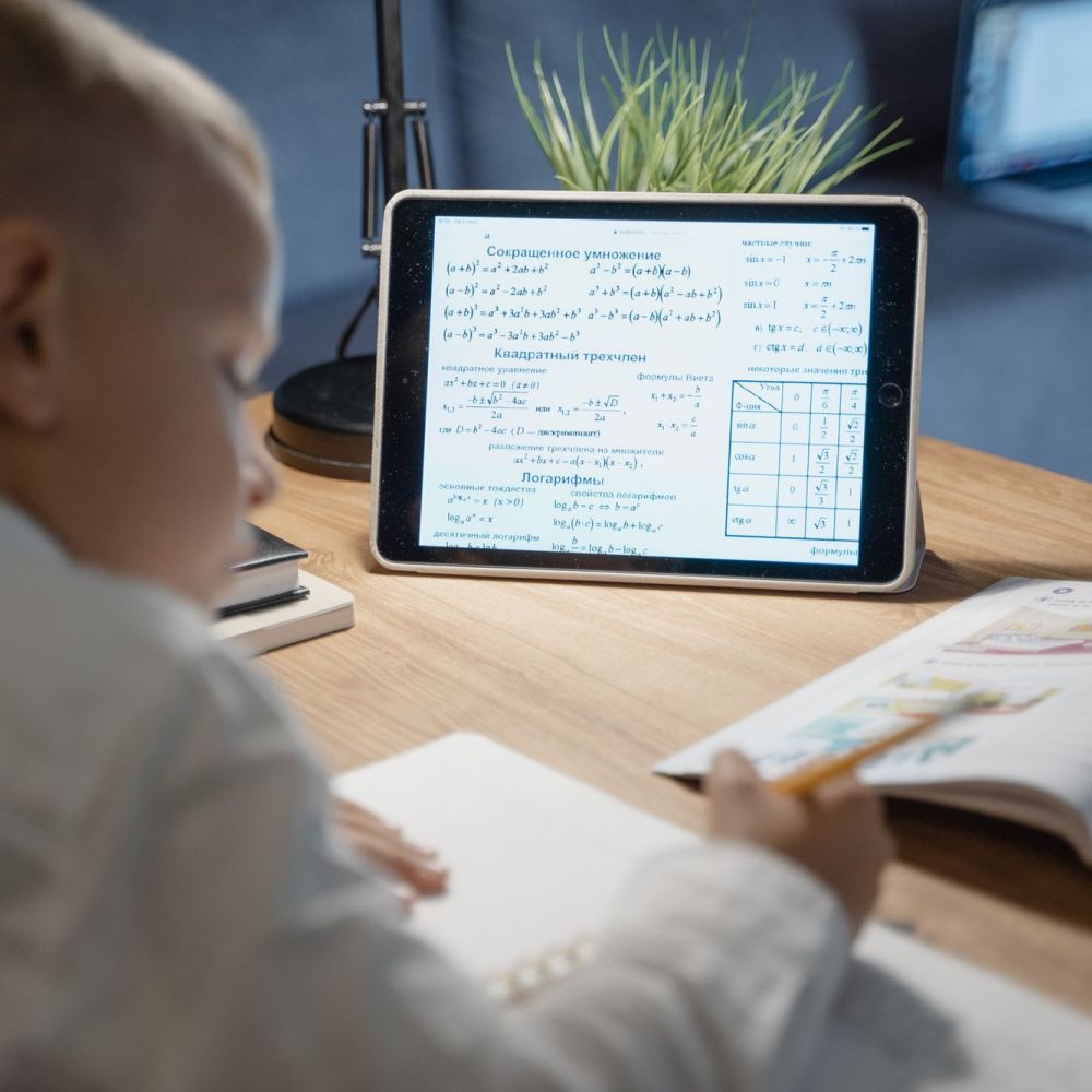 Kind oefent rekenen met een tablet en lesboek